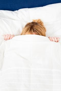 Woman lying underneath a down comforter
