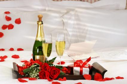 champagne, chocolates, rose petals on bed