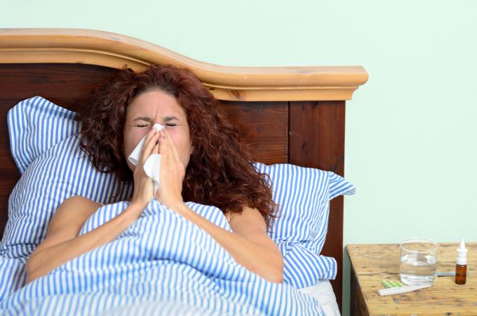 Woman blowing nose in bed