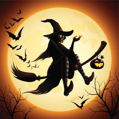 Witch riding a broom past the Halloween moon