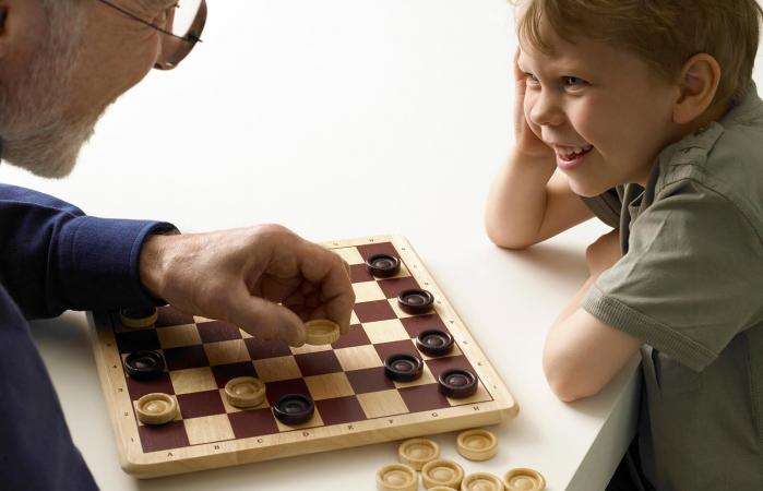 Boy playing checker with grandfather