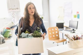 businesswoman carrying cardboard box in office