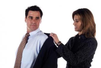 Wife helping husband put on suit coat 