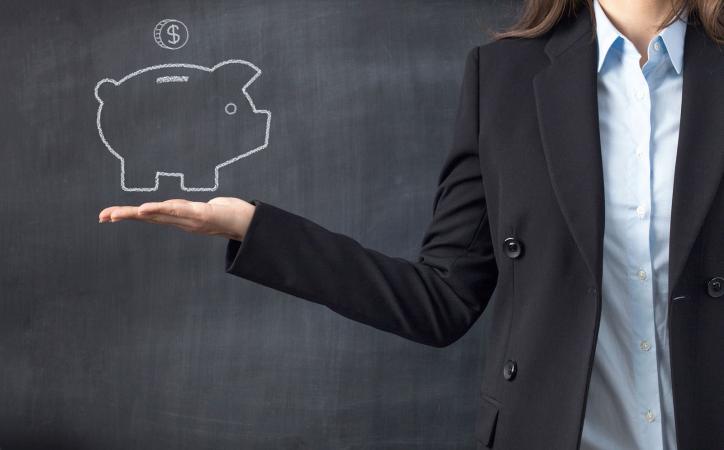 Holding piggy bank in front of chalkboard