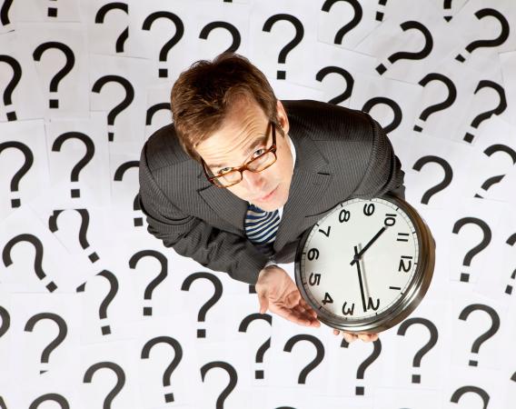 Businessman looking up holding a clock
