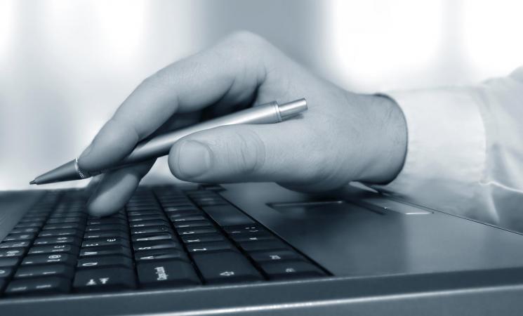 hand holding pen at keyboard