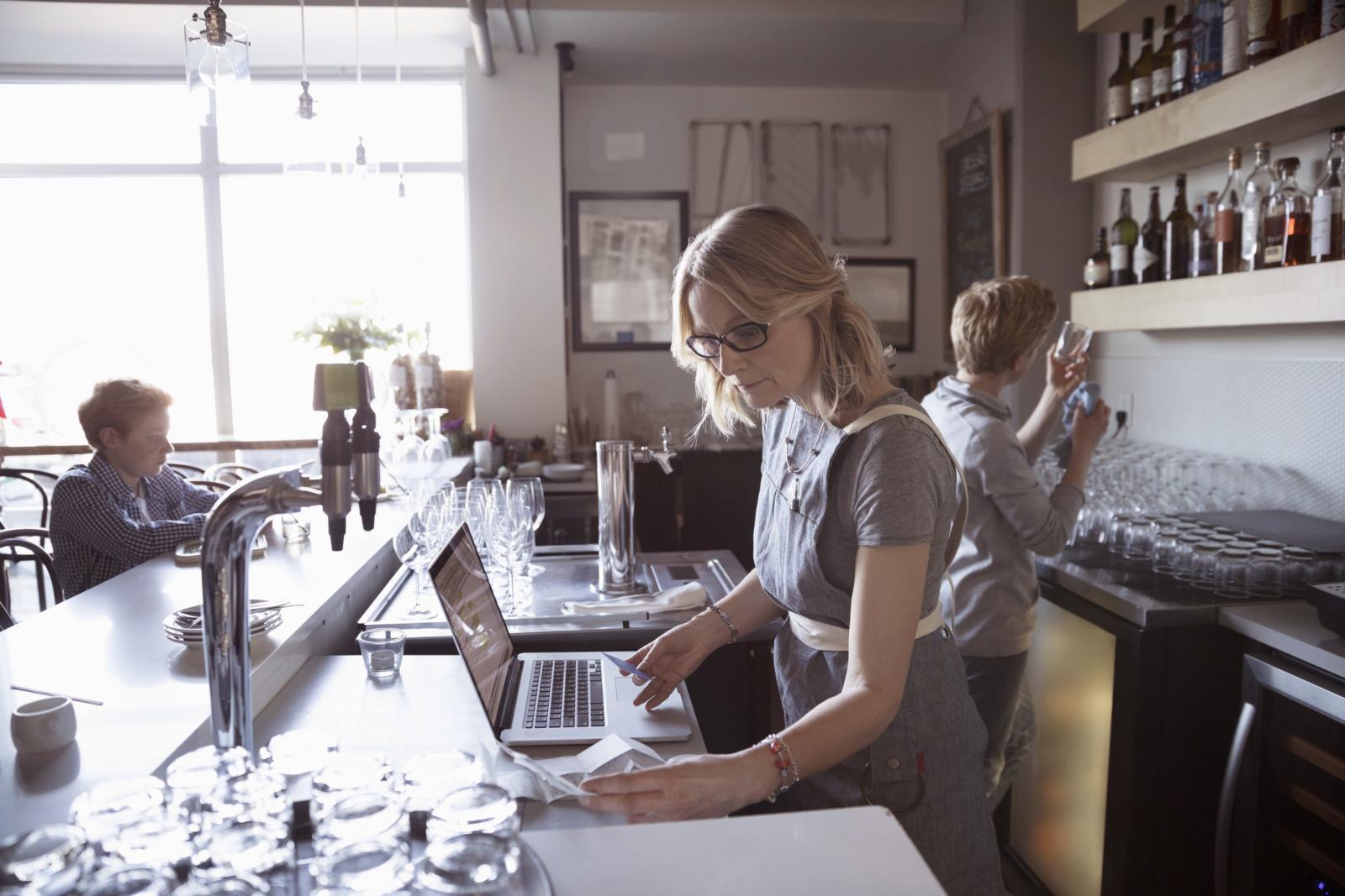 Family business owner working at laptop in cafe