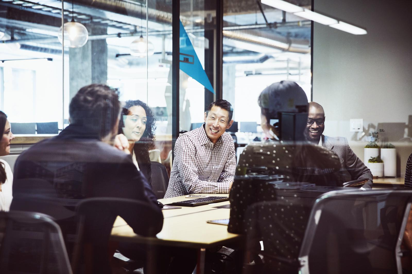 Smiling businessman leading client meeting in office conference room