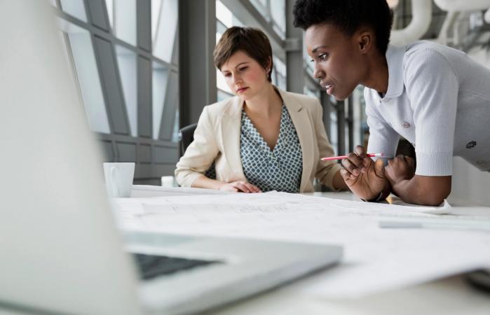Businesswomen looking at blueprint in office building