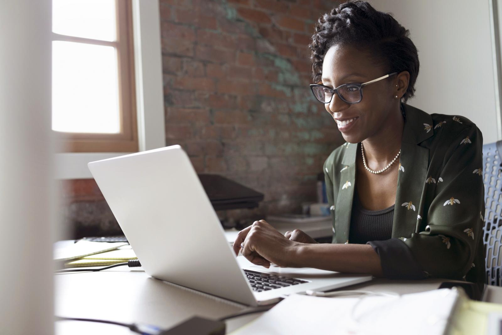 Smiling creative businesswoman working at laptop