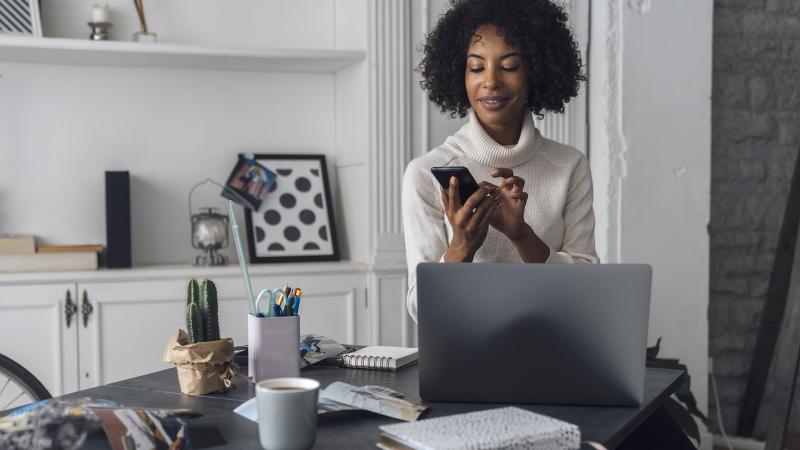 Woman working in her home office, using smart phone