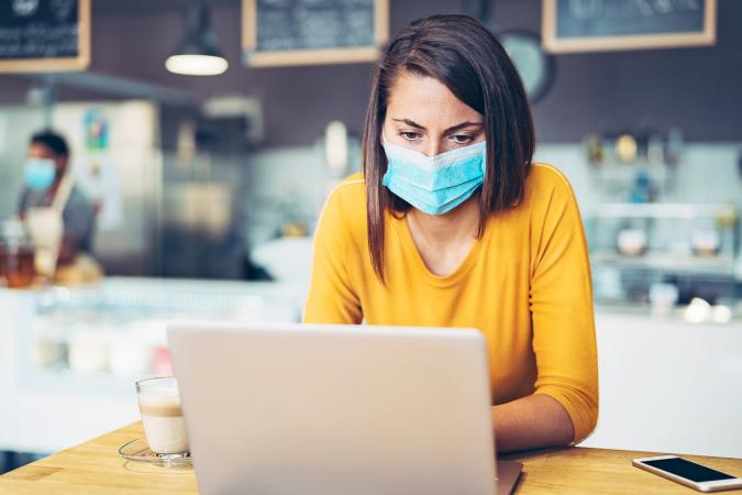 Worried woman with a face mask looking at a laptop