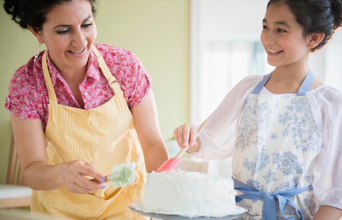 Mother and daughter decorating cake together