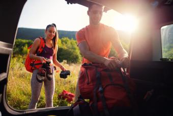 Young couple taking backpack out of car trunk in nature