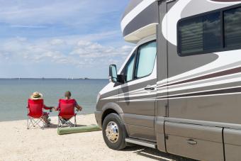 Senior couple sitting near water with motorhome in camping
