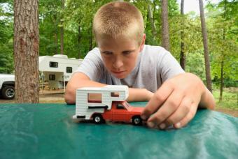 Young boy playing with pickup camper toy in campground