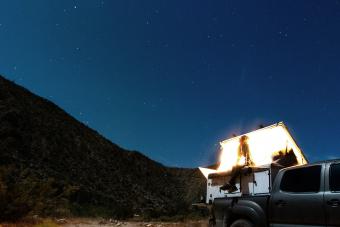 Woman looking up at a scenic desert sky on her camper truck