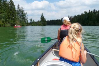 Mother With Daughter Rowing Boat On Lake