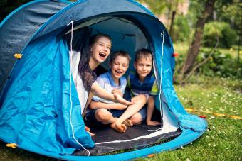 Kids happily sitting inside of blue tent