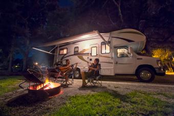 Couple and baby daughter sitting in front of campfire at night