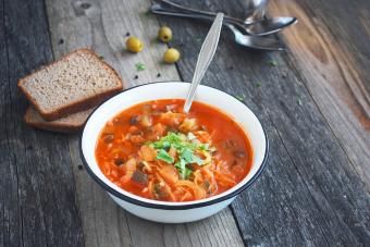 Soup with cabbage, tomatoes, mushrooms in rustic table