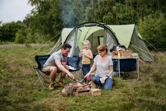 Family with one child cooking over open fire on camping trip