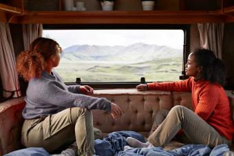 two female friends looking out window in camper van