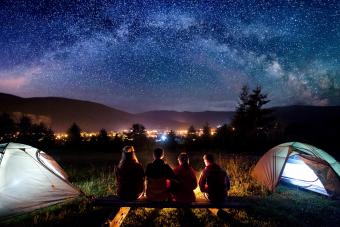 Family watching the stars beside camp and tents