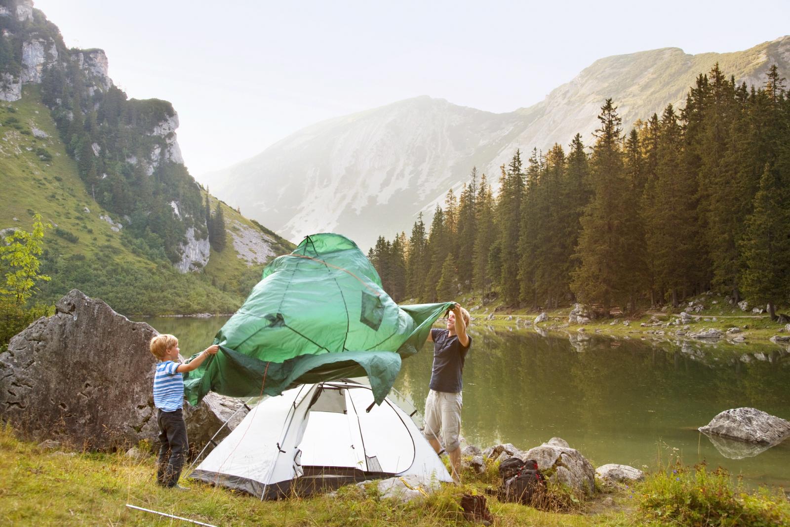 Father and son pitching a tent by lake