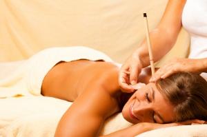Woman receiving ear candling treatment