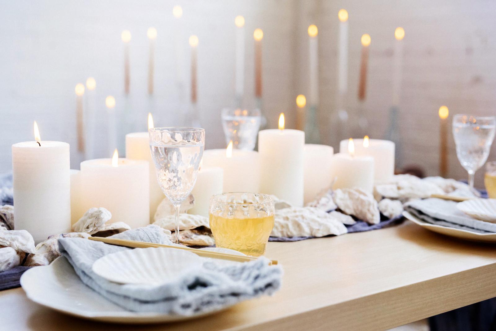 A table with lit candles, china plates and glasses