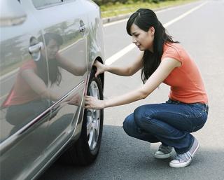 Woman looking at car tire