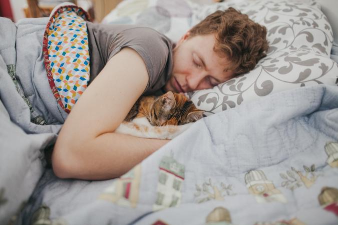 Man and cat asleep in bed