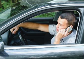 Young man speaking on phone while driving