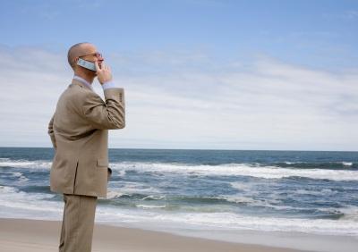 Businessman using phone on beach