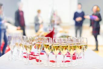 Banquet event. Table with the wineglasses, snacks and cocktails. People celebrating in the background