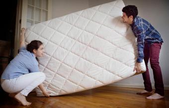 Couple carrying mattress in room