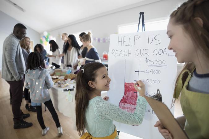 Girls filling in fundraising goal poster