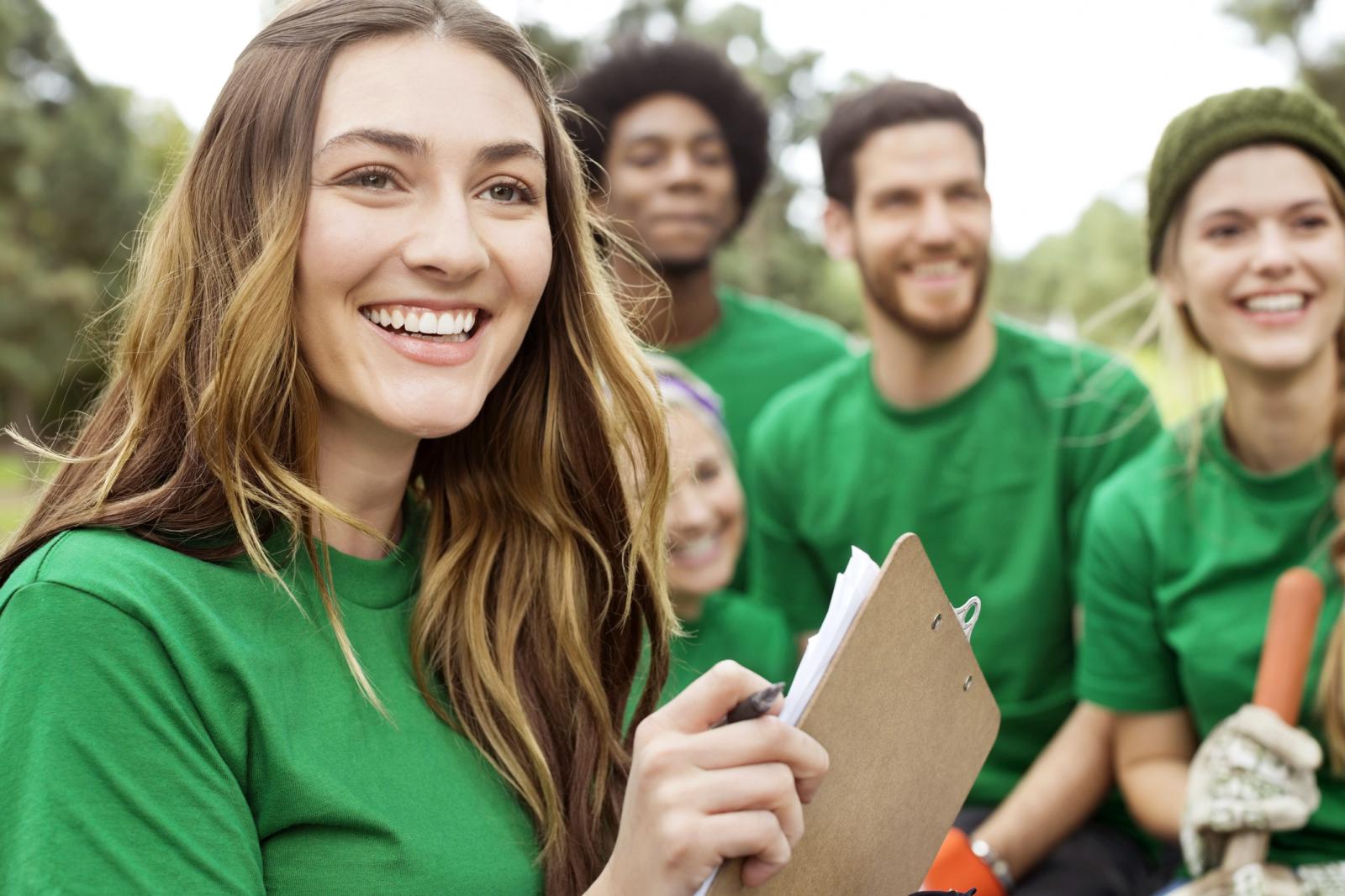 Environmentalist holding clipboard with volunteers in background