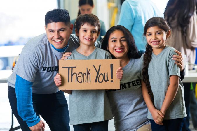 Family volunteering together and holding Thank you sign