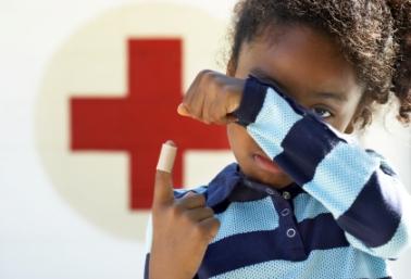 Little boy by Red Cross sign