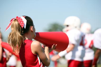 Cheerleader with megaphone and players in the background