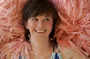 Cheerleader resting on poms