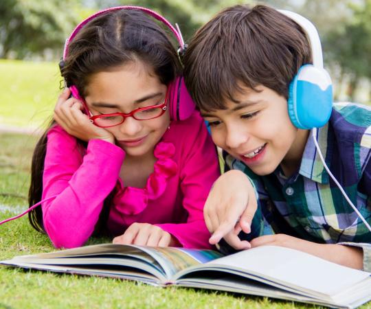 Kids with headphones reading a book