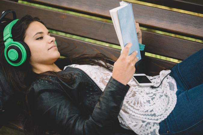 Girl reading book with headphones on