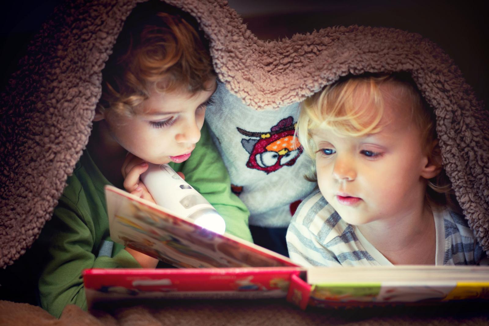 Children Looking in the Book Under the Blanket