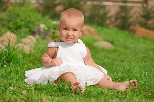 Baby girl in white dress on grass