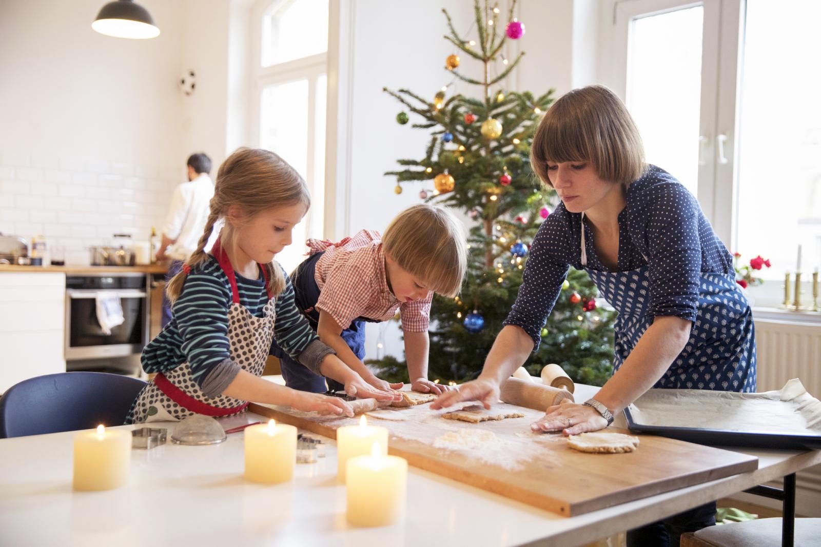 Modern mother making cookies with daughter and son at christmas