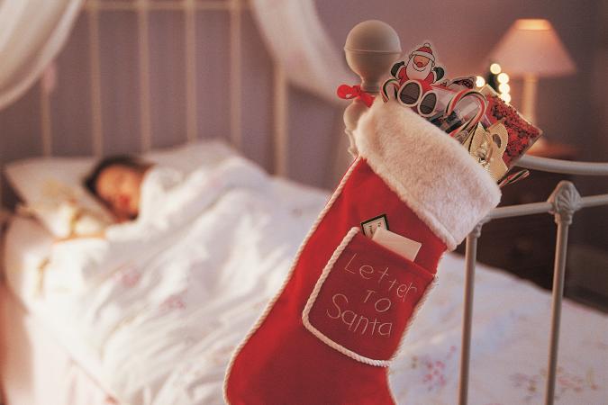 Christmas Stocking Hanging on a Bed Knob and a Child Sleeping in Bed
