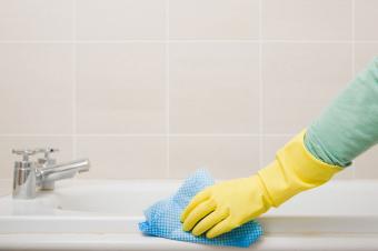 Woman cleaning tub with gloves on